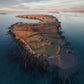 Picture of Castle Island at sunrise with old house ruins and grazing sheep in the foreground.