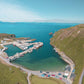 A photo print of the north harbour in Cape Clear island, showing its recently upgraded facilities. The calm waters of the inlet provide a safe haven from strong winds, and the picture captures the beauty of the island on a busy day