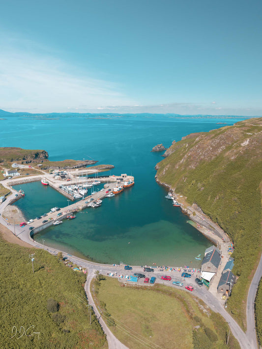 A photo print of the north harbour in Cape Clear island, showing its recently upgraded facilities. The calm waters of the inlet provide a safe haven from strong winds, and the picture captures the beauty of the island on a busy day